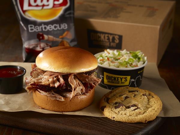 Pictured is Dickey's deluxe box lunch with a pulled pork classic sandwich, chips, side of crunchy cole slaw and a chocolate chunk cookie in a conveniently portioned box.