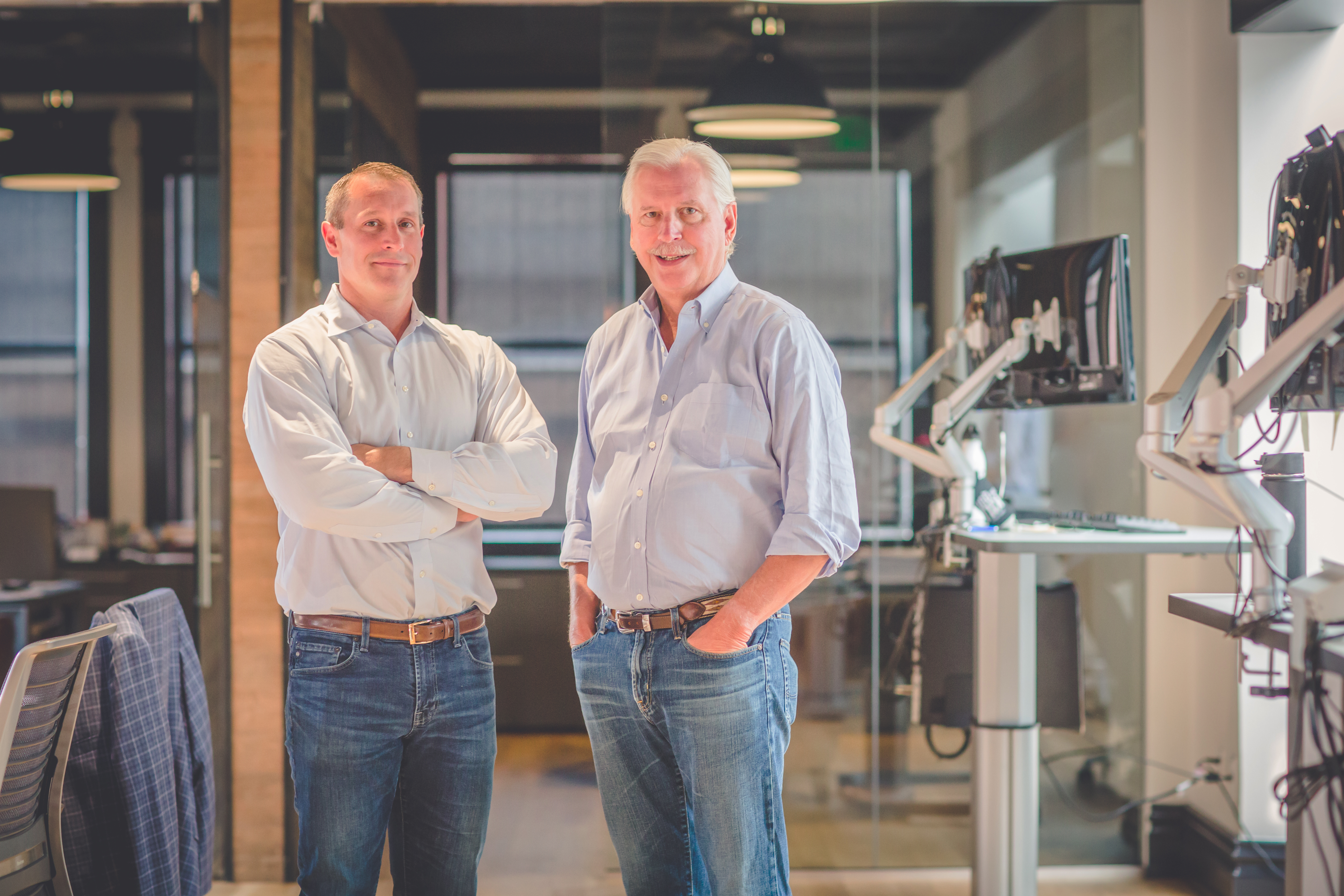 two men standing in an office in blue shirts