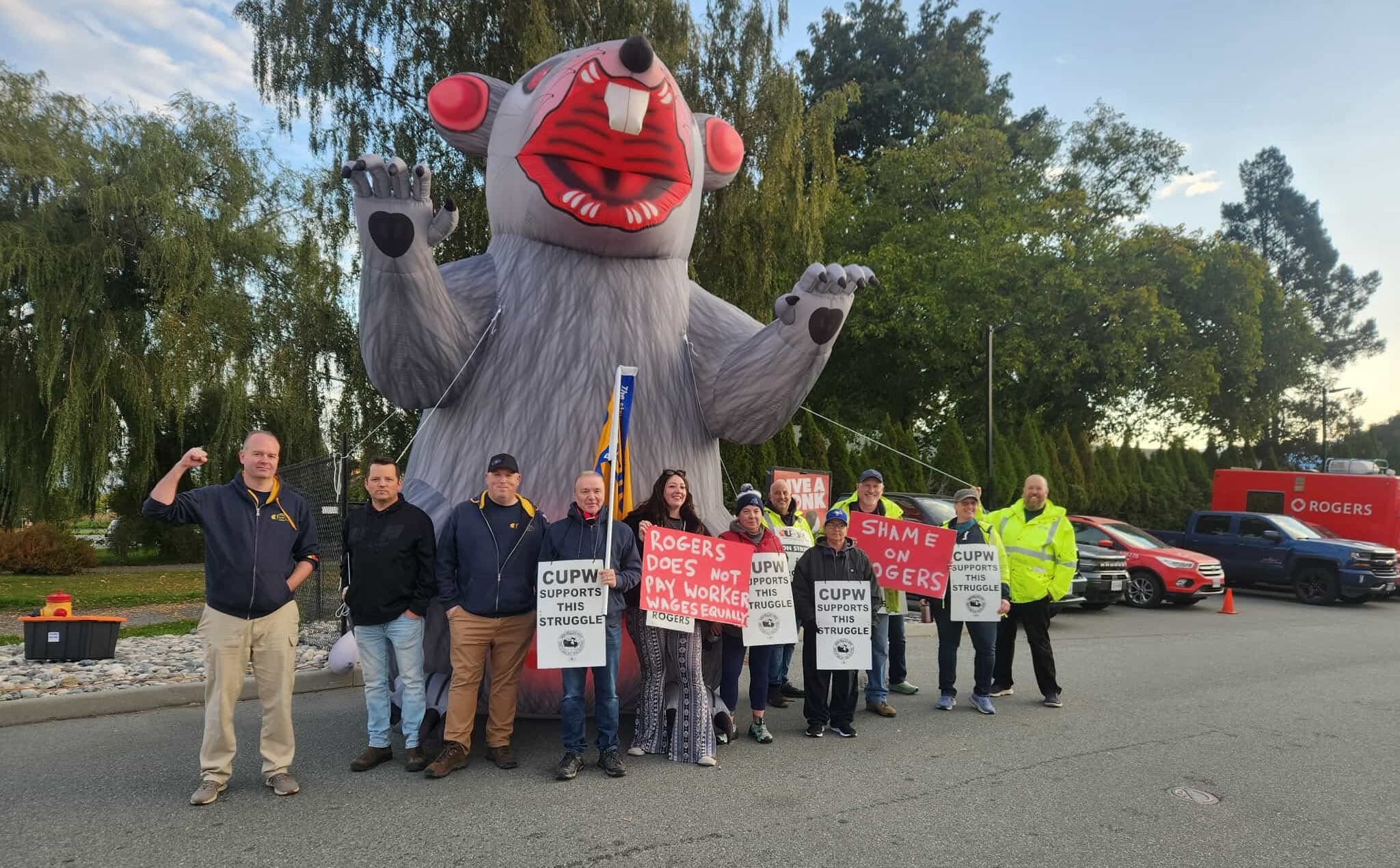 Striking workers standing in front of a giant inflatable rat.
