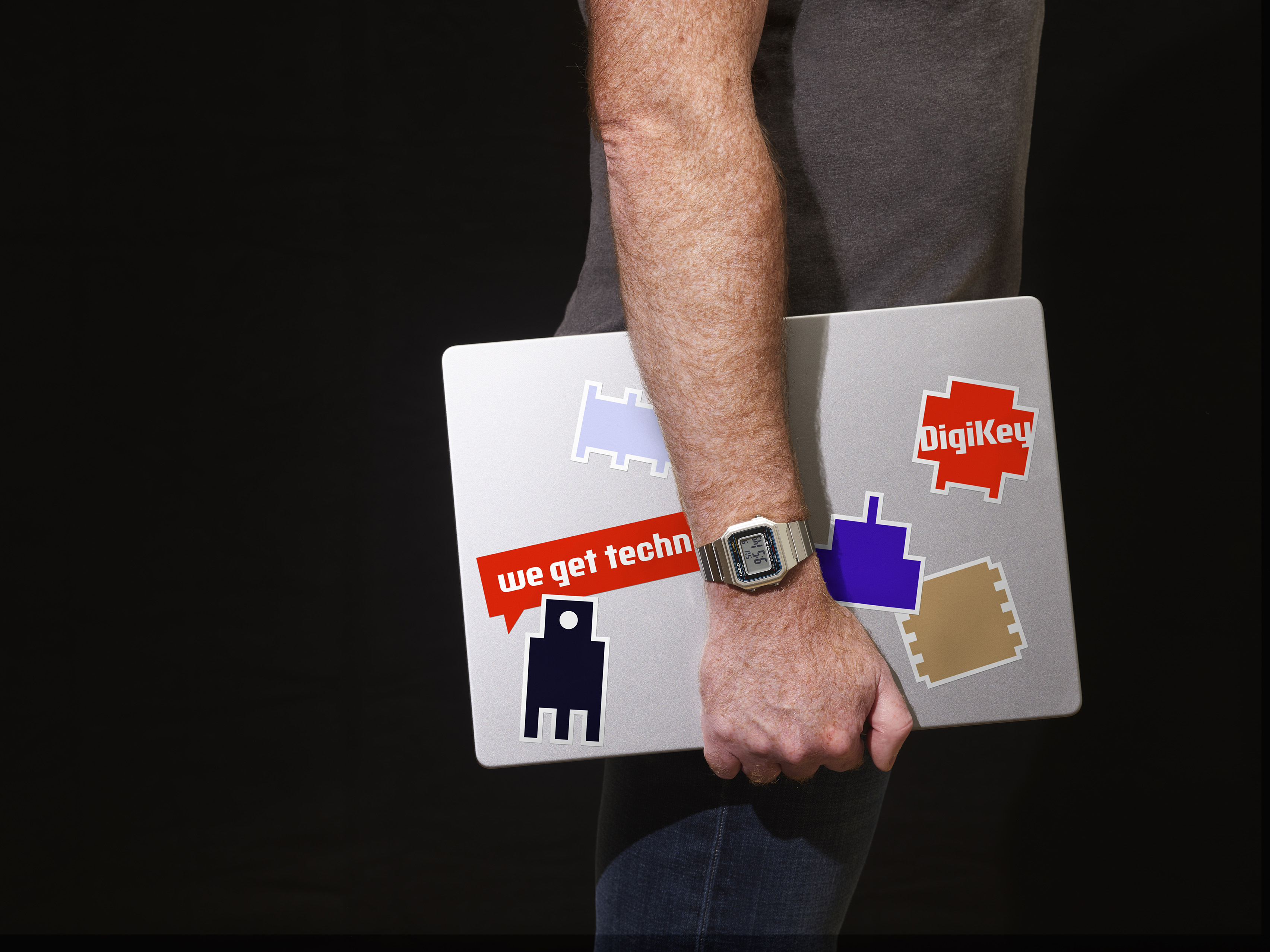 Male hand holding a laptop with DigiKey brand stickers on it