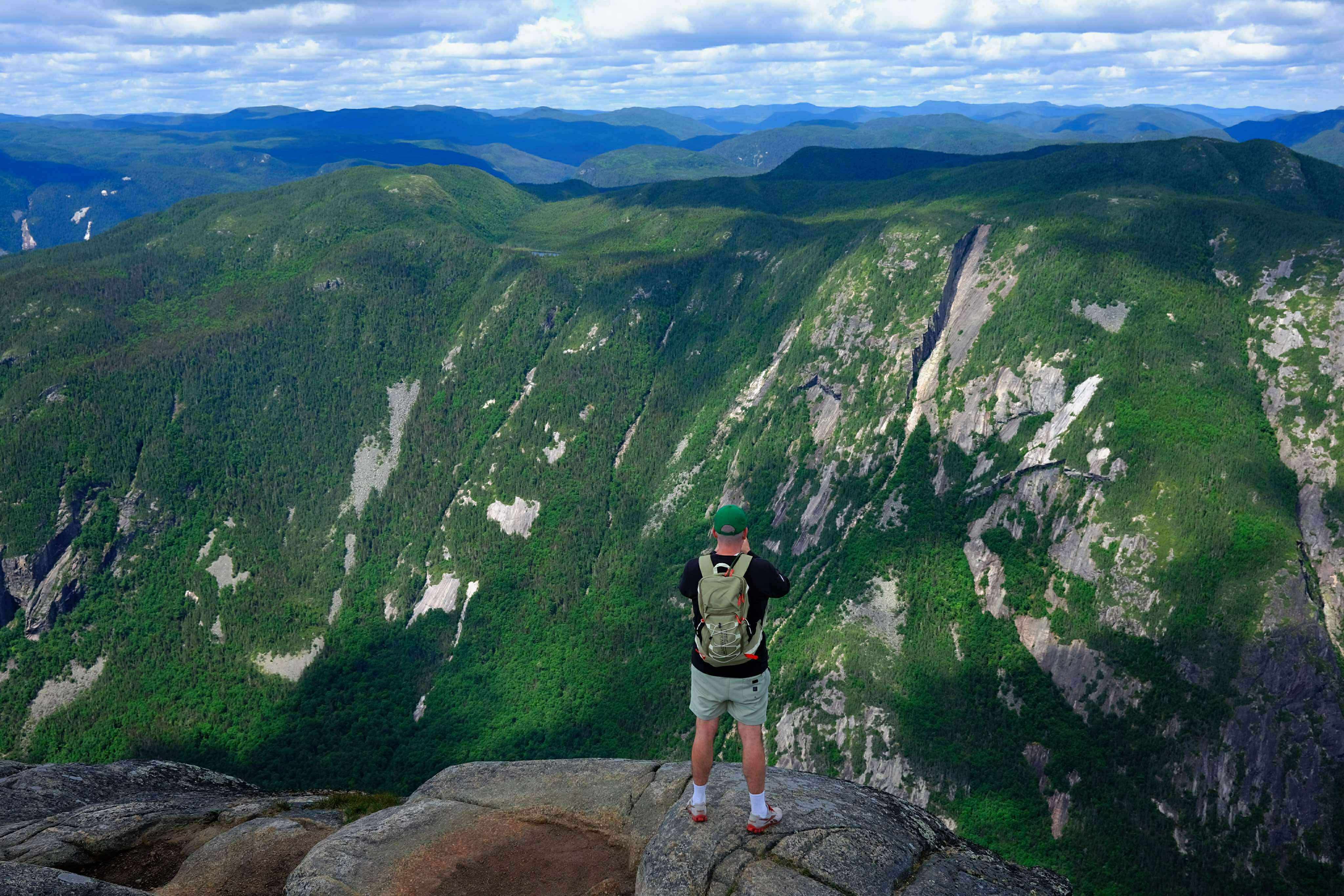 Yanik Guillemette au sommet de l’Acropole des Draveurs dans Charlevoix, surplombant les montagnes et forêts du parc national des Hautes-Gorges-de-la-R
