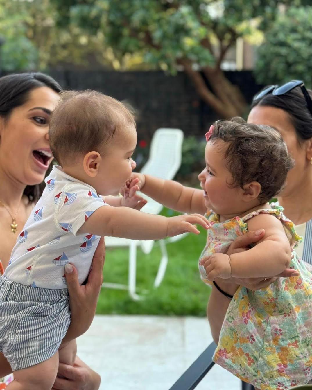 Two babies reaching toward each other at an Expecting Together reunion event, showing lasting community bonds beyond prenatal classes.