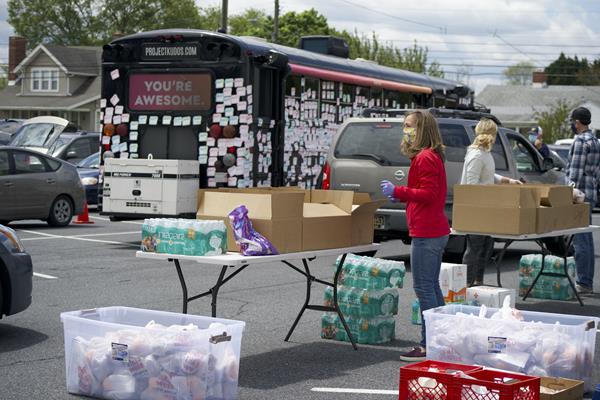 The Project Kudos Bus parked by Schell team member distributing food boxes to families in need. 