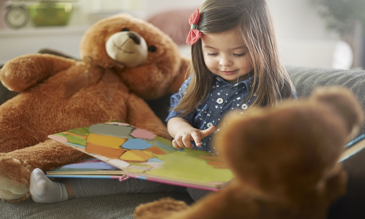 Child reading to her toy teddy bears