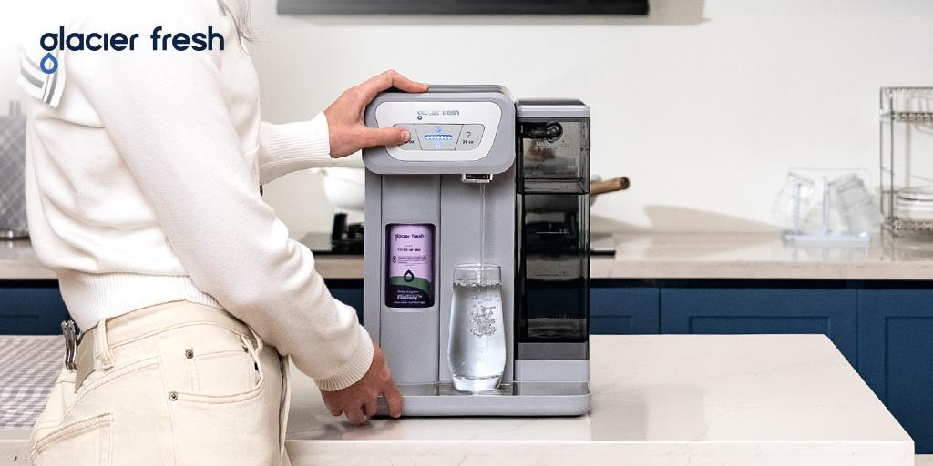 A girl is using the Glacier Fresh Coolon Cold Water Dispenser to serve her family.