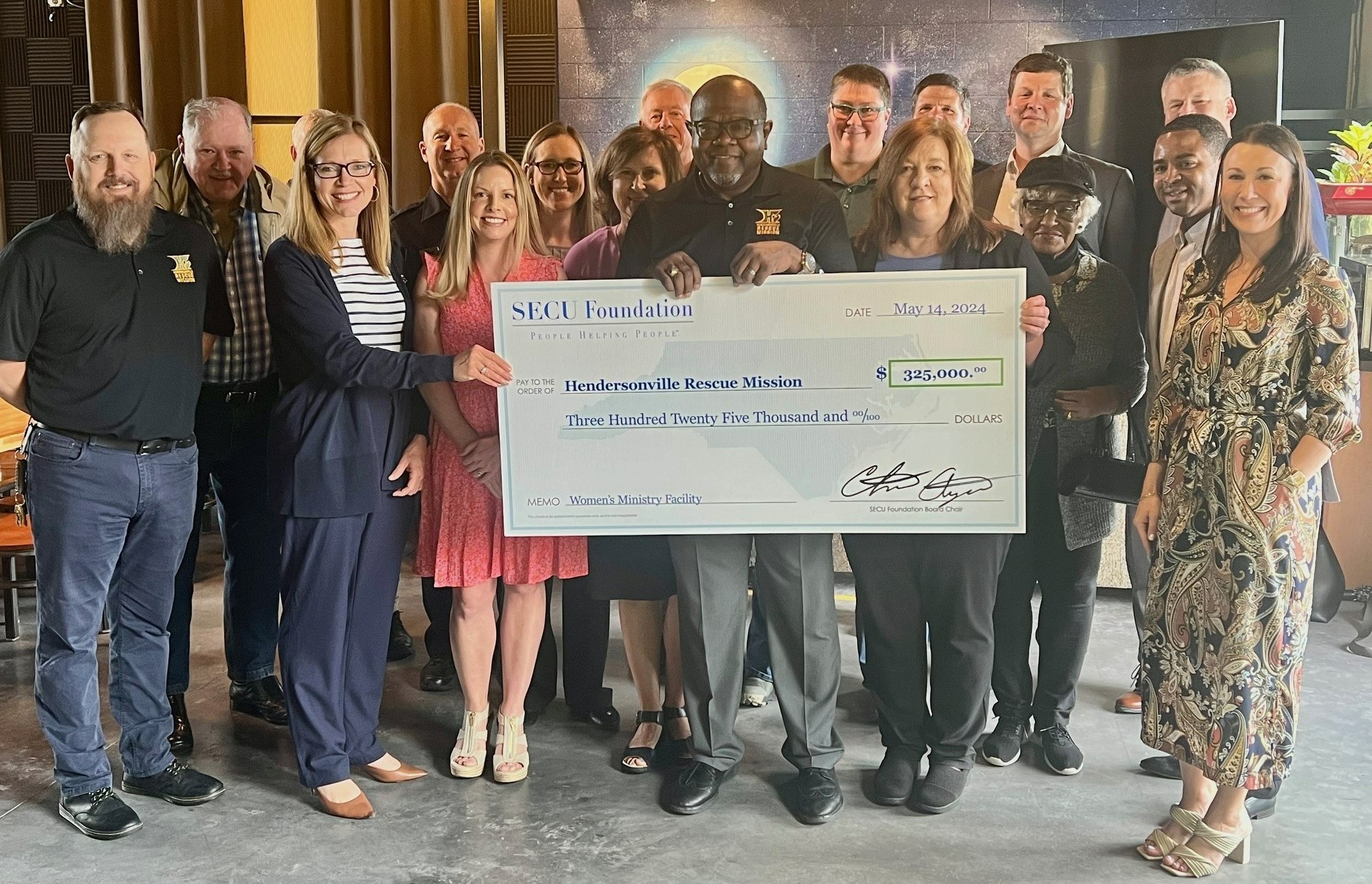 Holding check left to right are HRM Board Member and SECU Hendersonville Branch Advisory Board Member Laura Simpson; HRM CEO Reverend Anthony McMinn; and SECU Regional Senior Vice President Kim Hollifield, surrounded by SECU and SECU Foundation representatives.