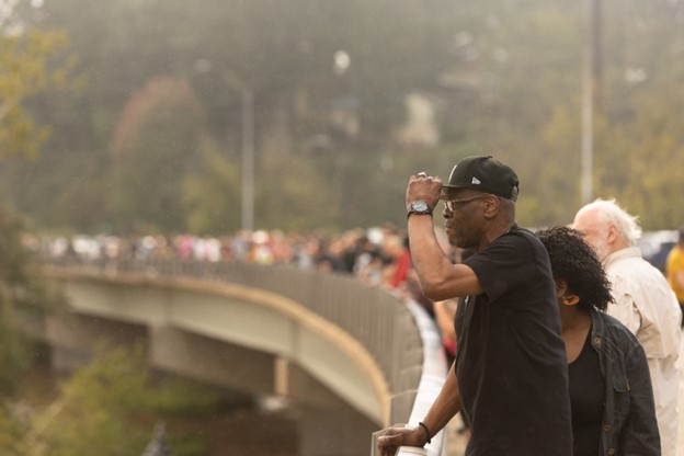 Asheville residents gather on a bridge overlooking the French Broad River after catastrophic flooding in Asheville’s River Arts District