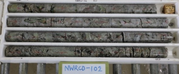 The pegmatites which comprise the orebodies occurs as a series of sub- horizontal sills, hosted by both volcanic and intrusive rocks, interpreted as a series of westward verging thrusts. Typical coarse grained spodumene (grey green colour) from the NW pegmatite shown above.