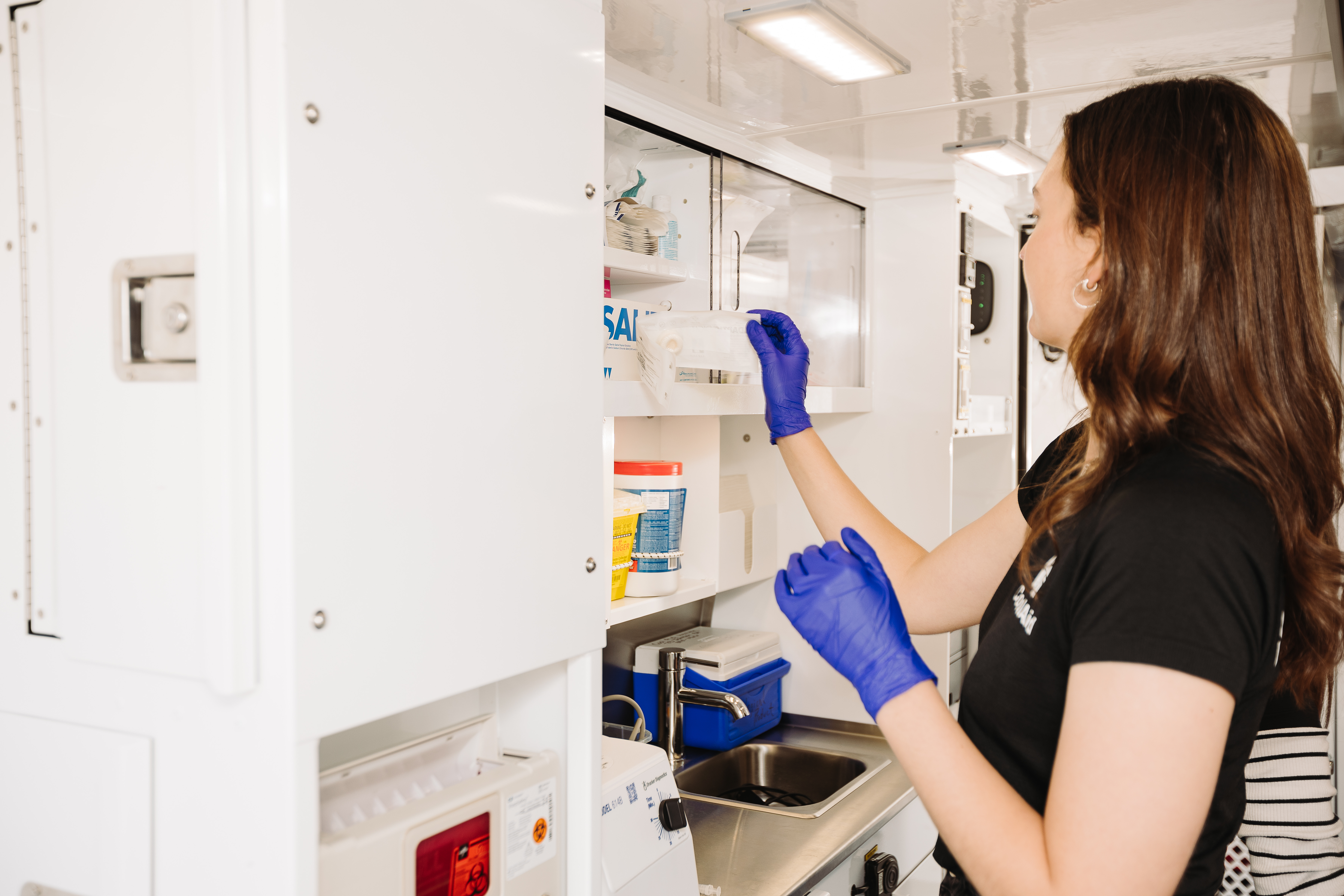 A mobile health clinic staff member retrieving medical supplies from a cabinet. 