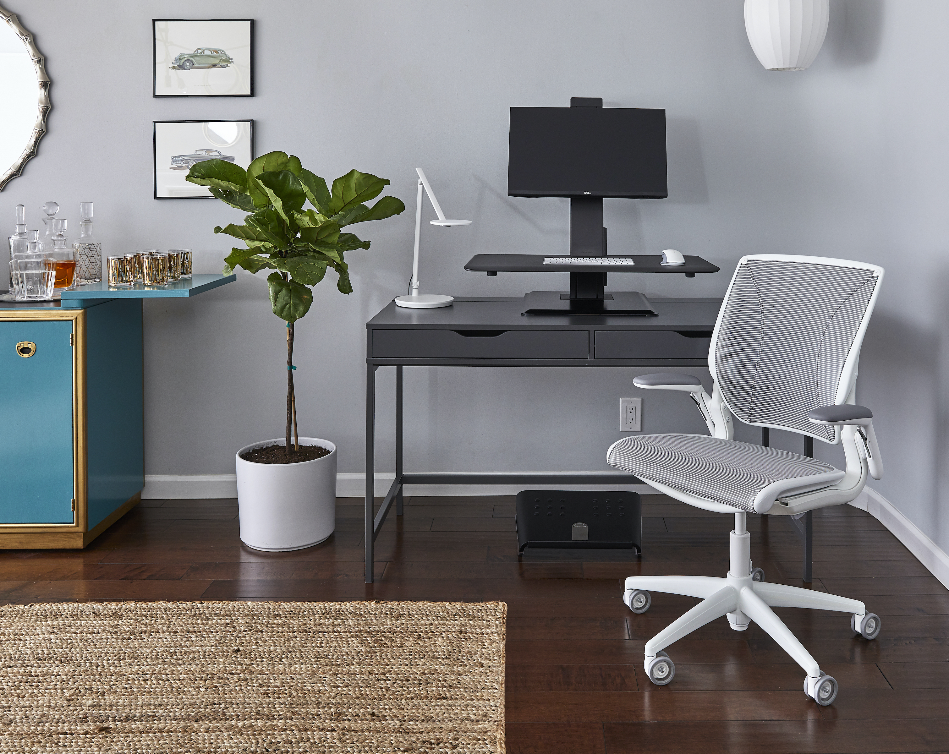 Home office featuring Humanscale's QuickStand Eco sit/stand solution, Nova task light with wireless charging base, Pro Click mouse, World task chair, and FR500 ergonomic foot rocker. 