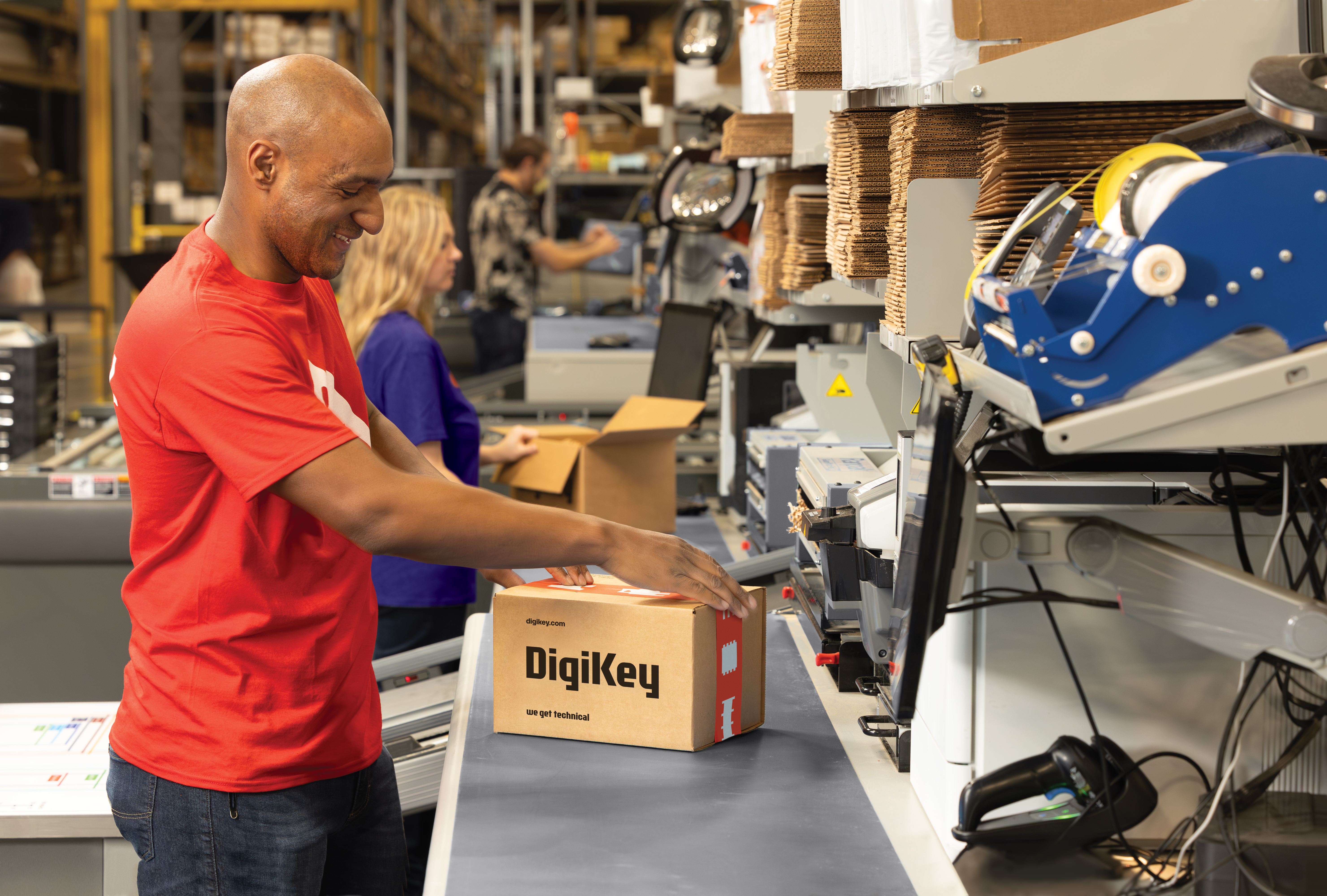 Man in red shirt packing a DigiKey box on a conveyor line