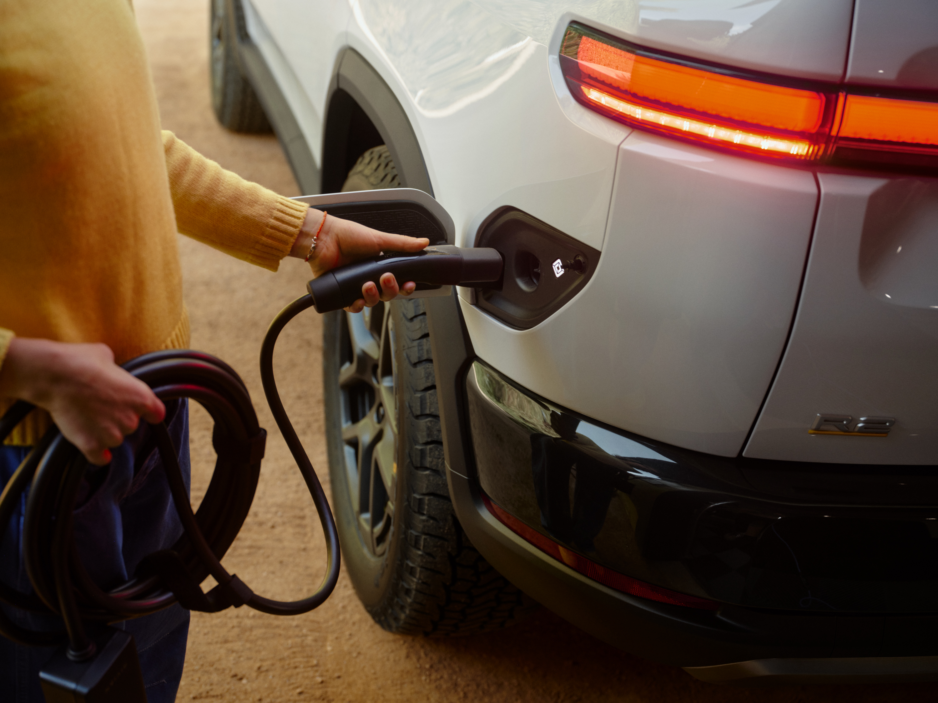 A Rivian R2 is plugged in to charge.
