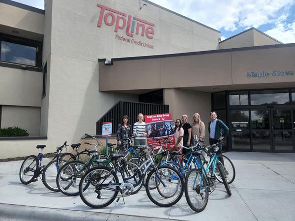TopLine employees and non-profit partners stand with bike donations.