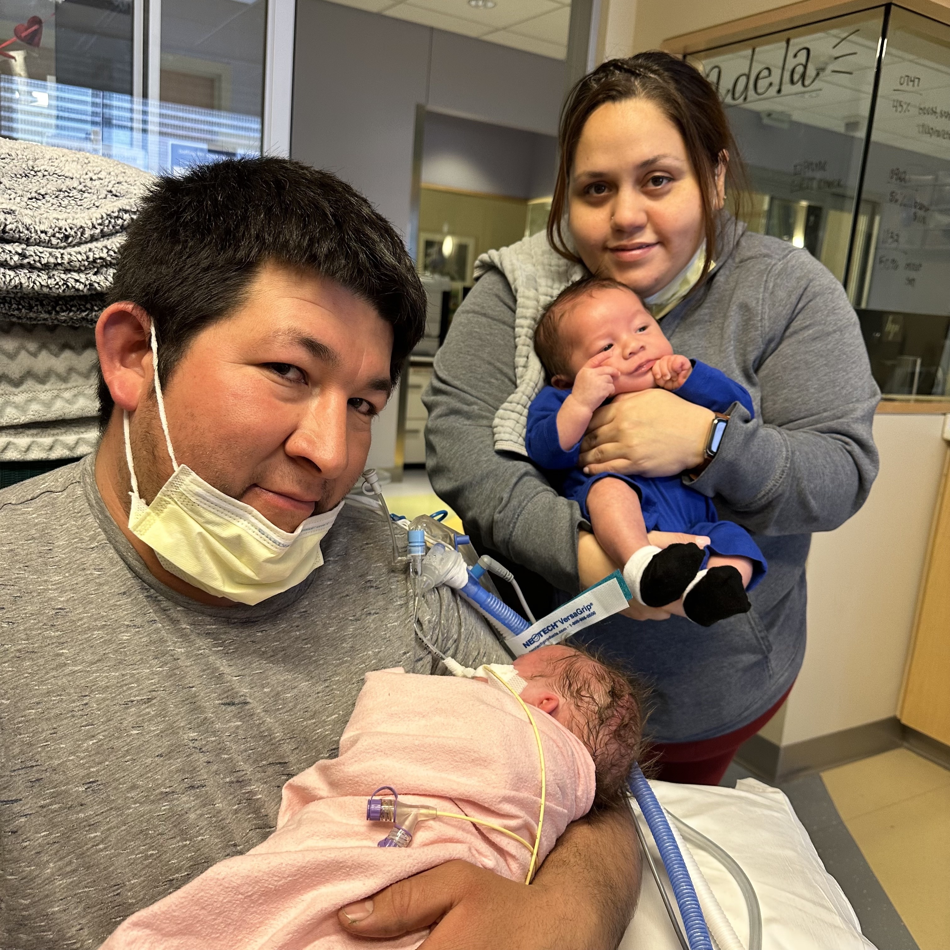 Mom and dad in the NICU with their two premature babies supported by There with Care