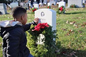 Young boy places wreath