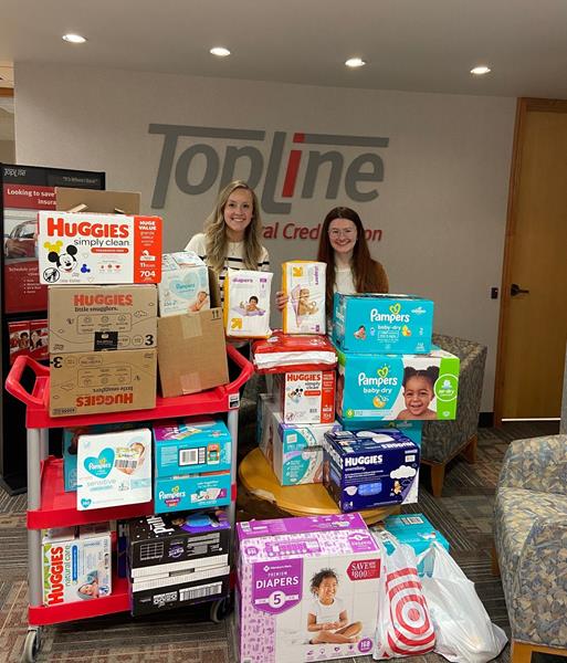 TopLine employee and community partner stand with baby diaper and wipe donations