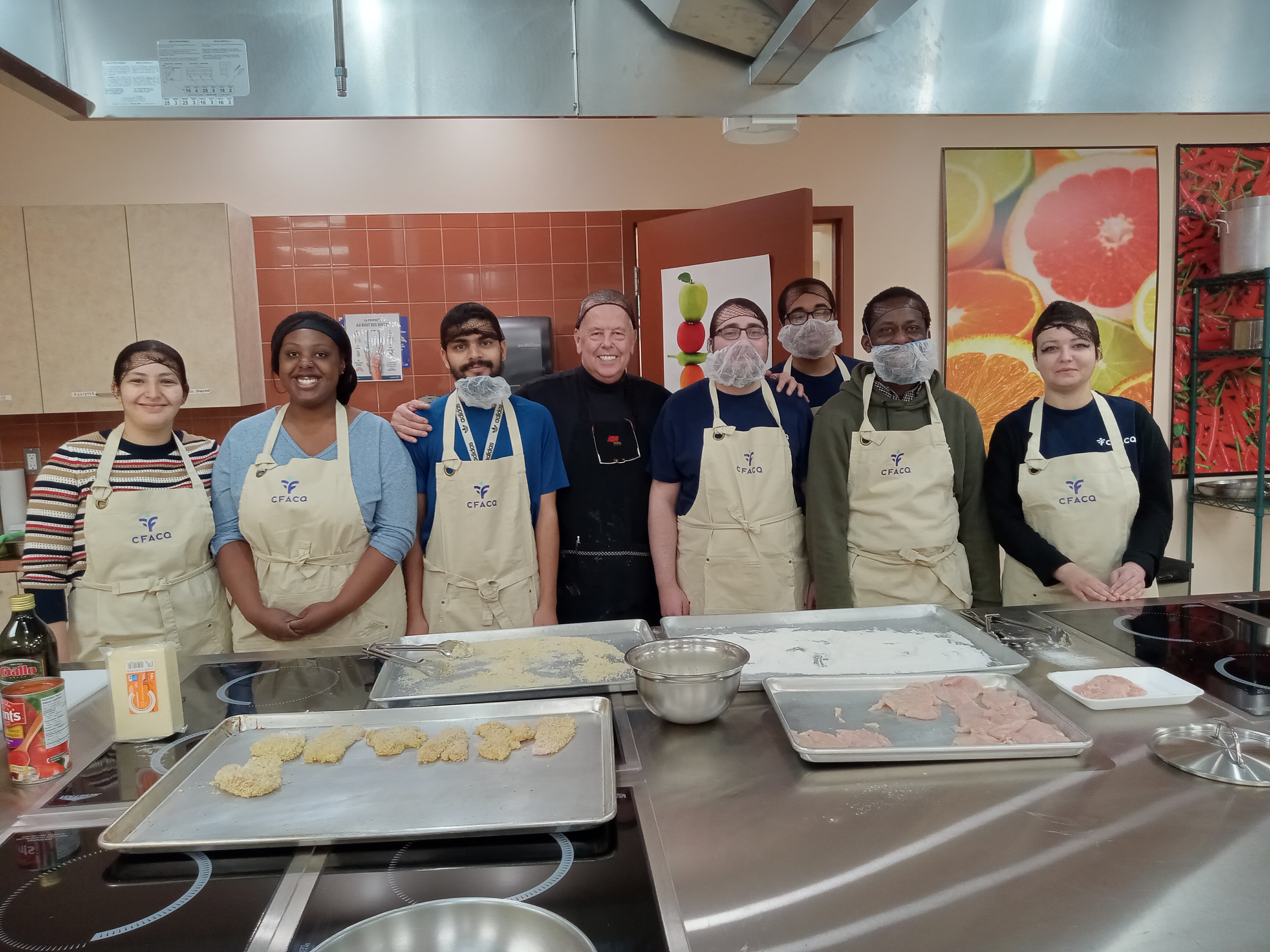 Des apprenants dans la cuisine-école avec leur formateur.