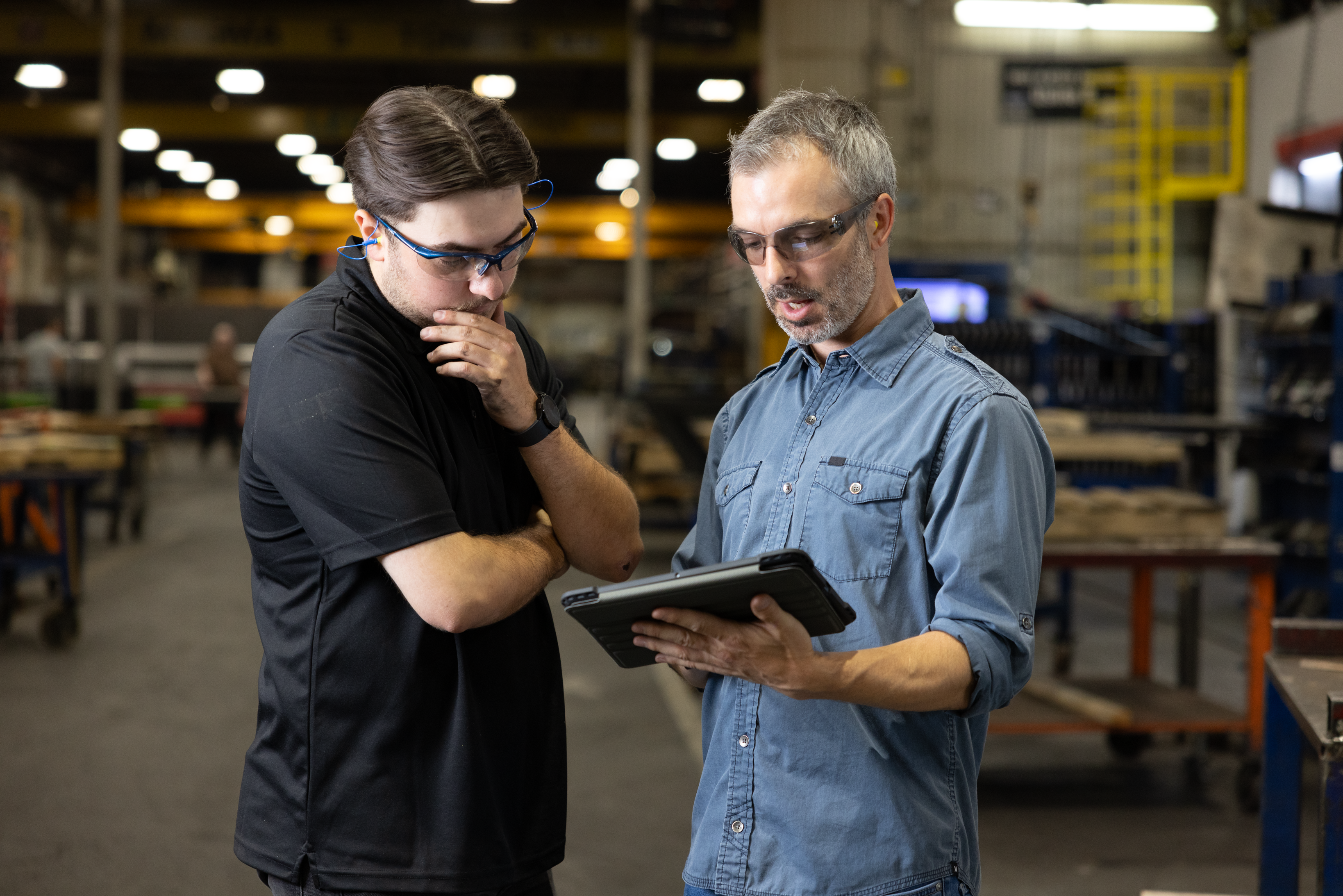 Un responsable des opérations senior consulte les données de la flotte sur une tablette avec un technicien dans un environnement de production.