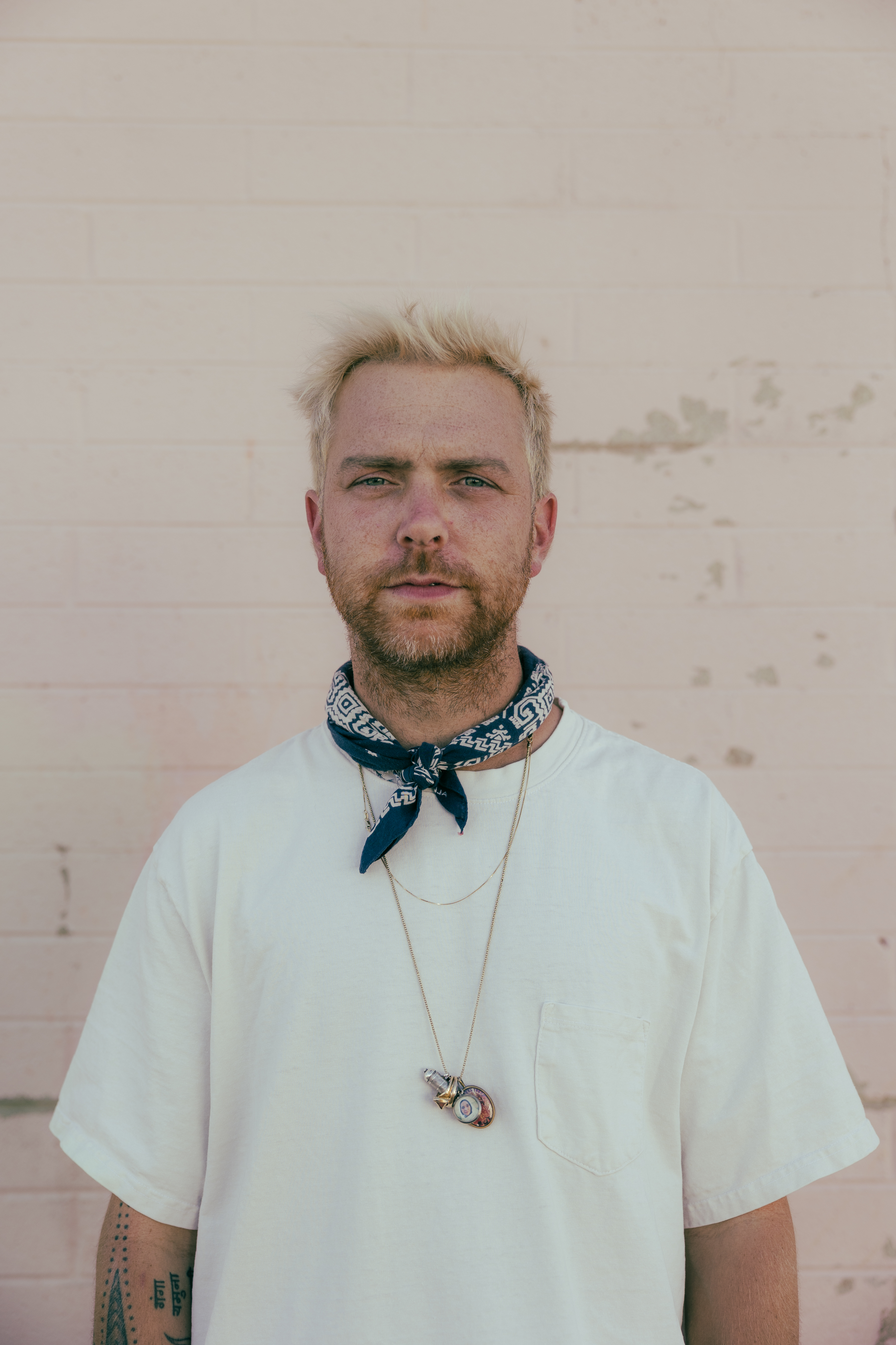 Image shows music artist trevor hall in a t-shirt and bandana around his neck.