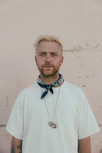 Image shows music artist trevor hall in a t-shirt and bandana around his neck.
