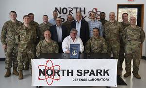 U.S. Air Force Col. Timothy Curry, 319th Reconnaissance Wing commander, the Bakken Energy Team, and the North Spark Defense Laboratory team pose for a photo Nov. 15, 2022, at the North Spark Defense Laboratory on grand Forks Air Force Base, North Dakota. Curry signed an agreement partnering with Bakken Energy to allow Grand Forks AFB to implement alternative energy solutions. (U.S. Air Force photo by Senior Airman Roxanne Belovarac)