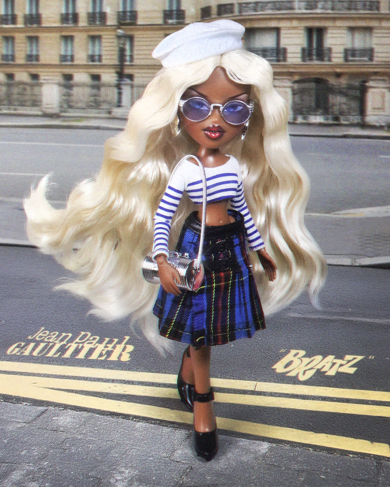 In one of the most iconic doll collaborations to date, Bratz inducts Jean Paul Gaultier into their designer doll collab hall of fame. Fearless fashion meets Parisian couture in this ultra-premium doll.  Sasha's second look is inspired by the Jean Paul Gaultier ready-to-wear collection and channels a nautical spirit with a chic punk twist, featuring a crisp marinière crop top, a pleated tartan mini skirt with buckle accents and a white sailor hat that sits atop her waist-length blonde waves – a first for Sasha!