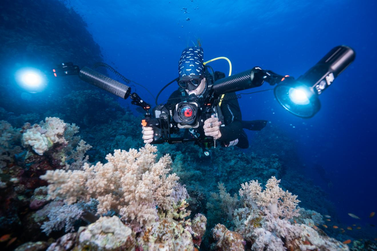 Diver with SeaTouch 6 Pro and dual lights over coral reef