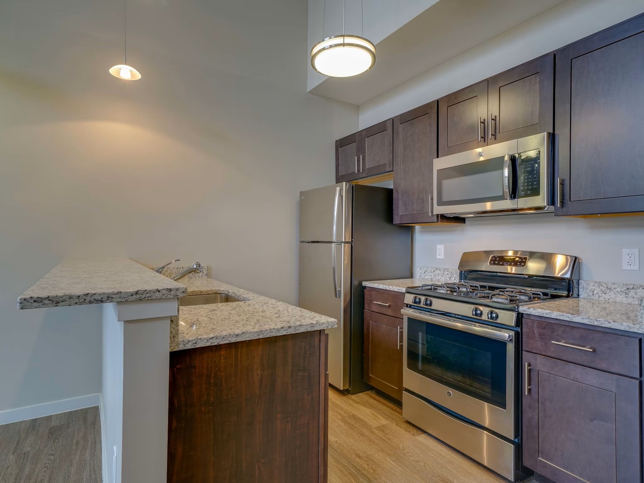 Modern kitchen at College & Crown apartments with stainless steel appliances and quartz countertops.