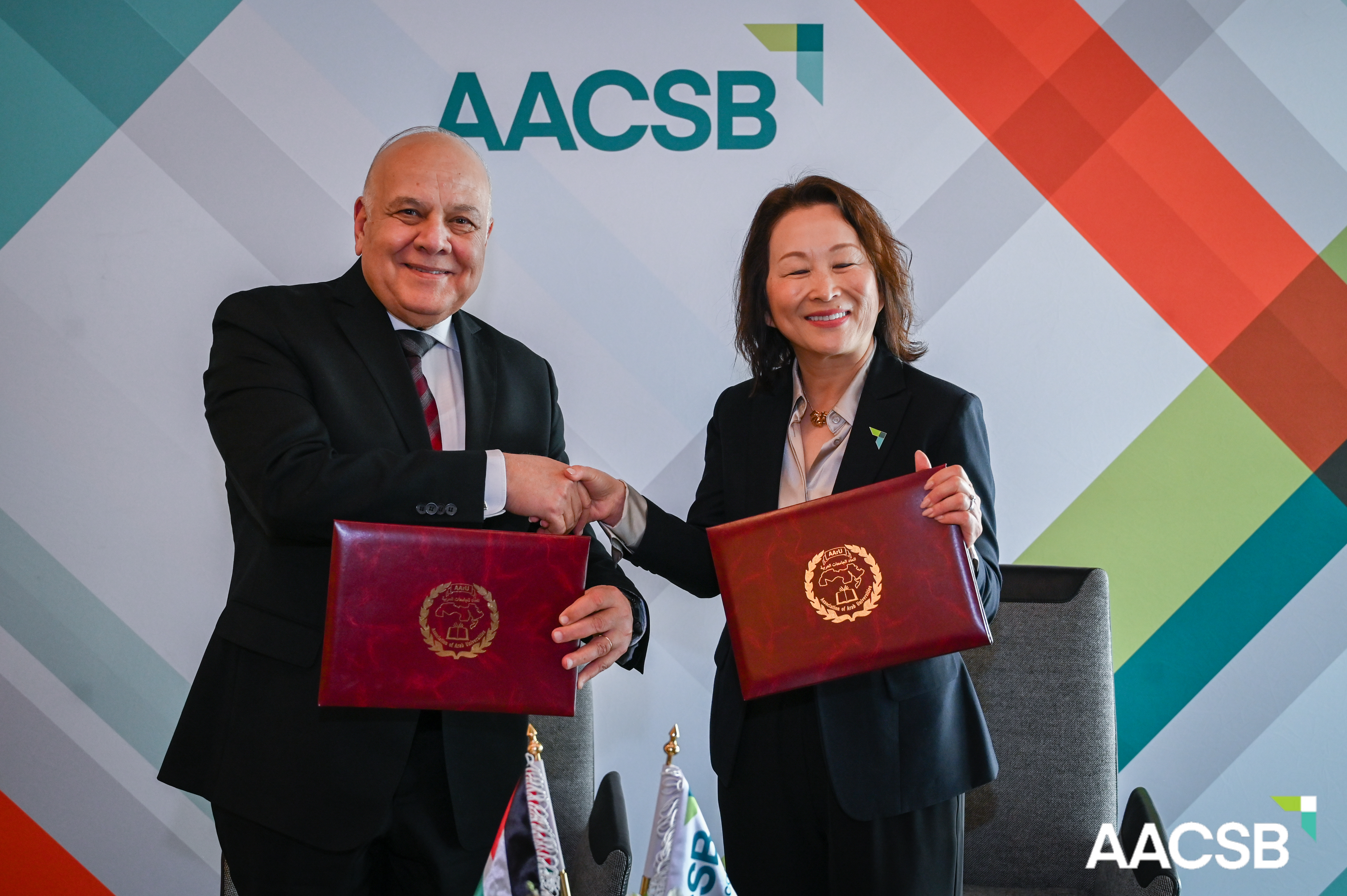 AArU Secretary General, Prof. Dr. Amr Ezzat Salama (left) and AACSB President and CEO, Lily Bi (right) shake hands after formally signing MOU at AACSB's MENA Conference in Dubai, UAE.