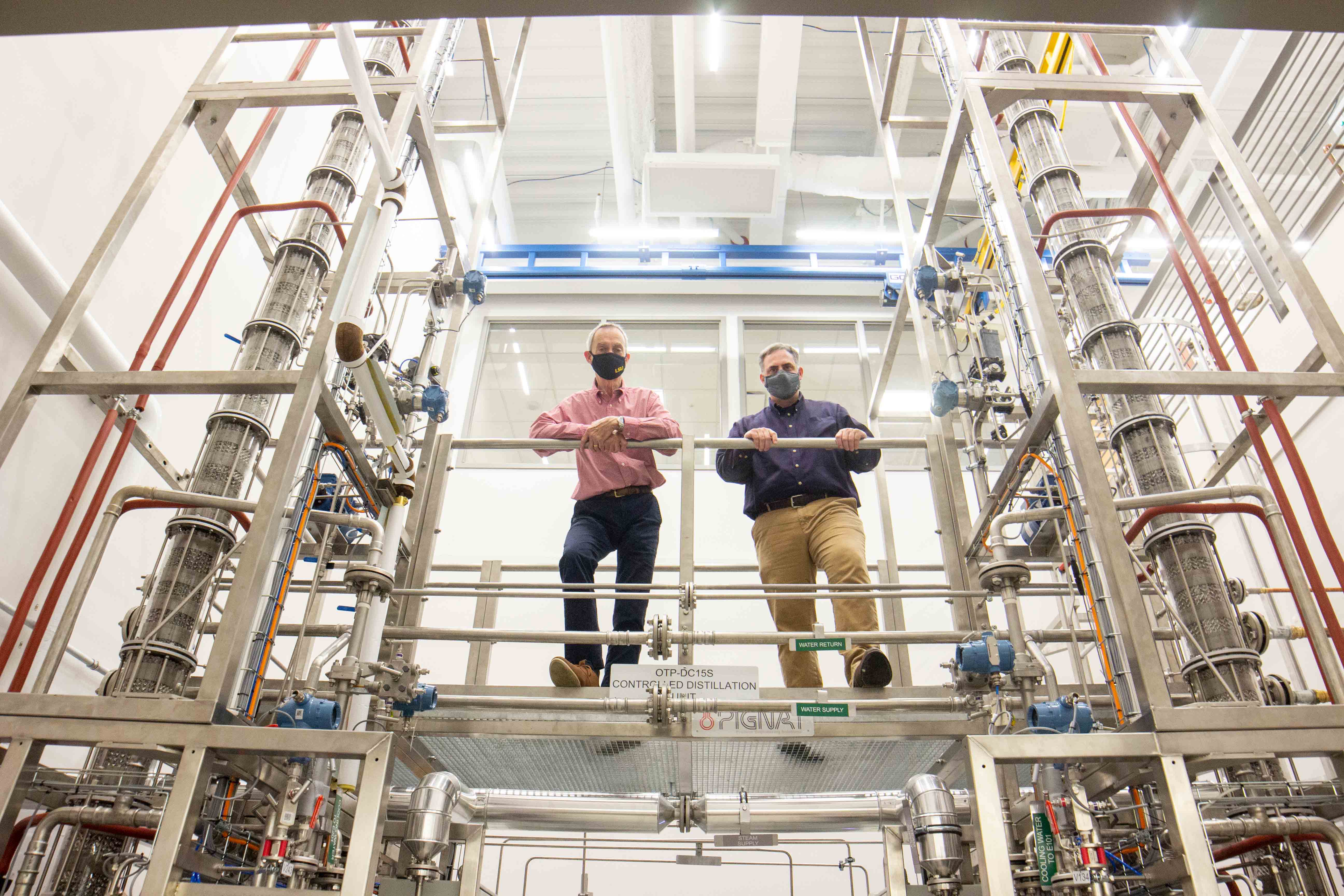 LSU Chemical Engineering Professional-in-Residence John Pendergast and Chair John Flake stand on the walkway of the department's new distillation columns.