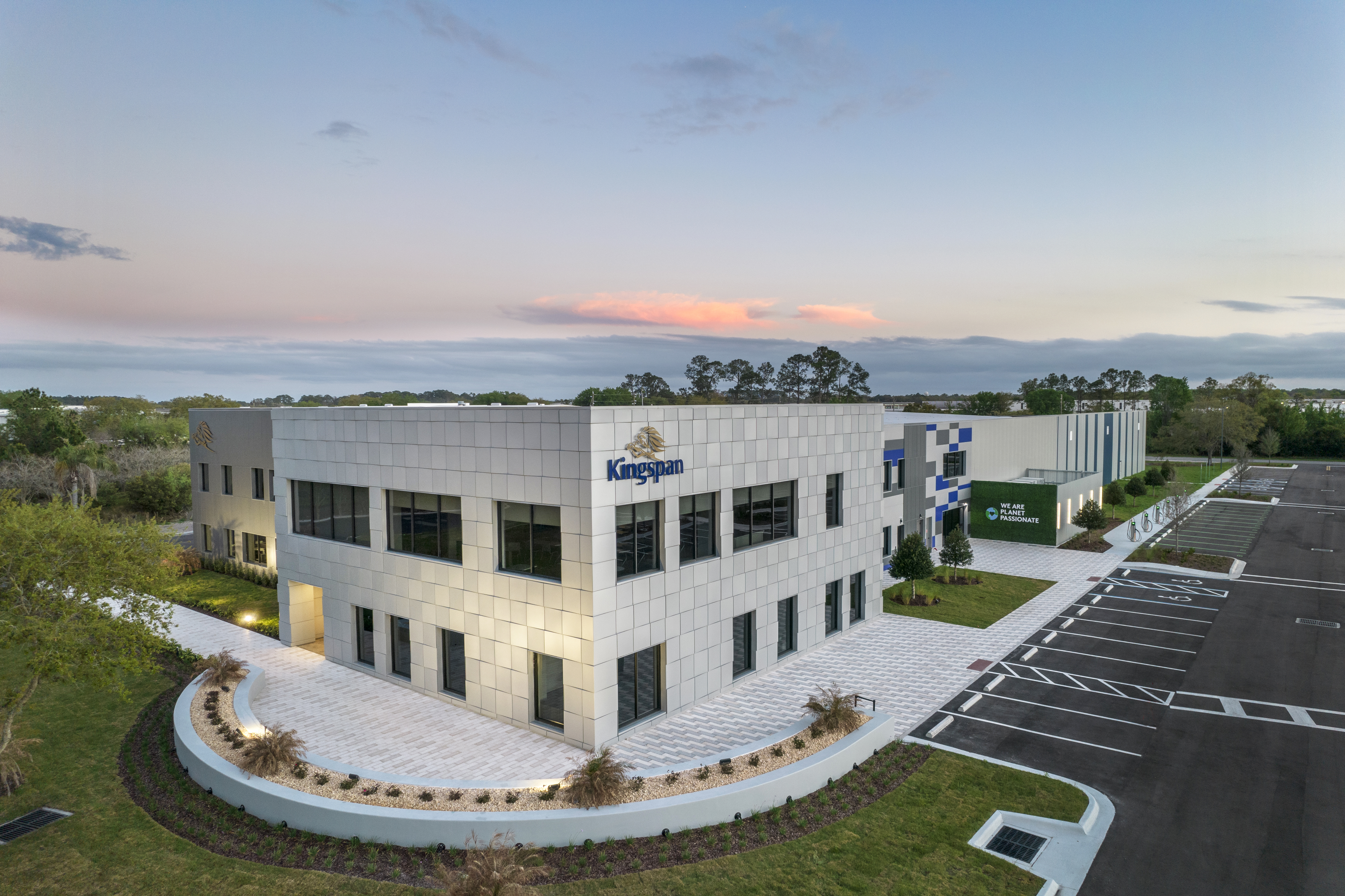 Aerial view of a modern structure with large windows and a well-maintained landscape. The Kingspan logo is visible on the front of the building.