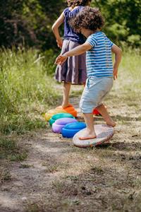 Image shows two children playing on Stapelstein elements using them like stepping stones and balancing on a board