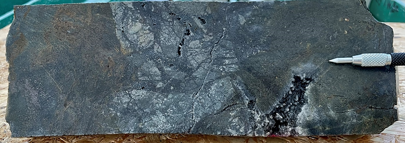CMVDD001 PQ-sized interval from 31.45 to 31.68 m features sulphide cemented breccia, semi-massive grey sphalerite with galena-stibnite-pyrite (2 cm scratcher tip for scale).