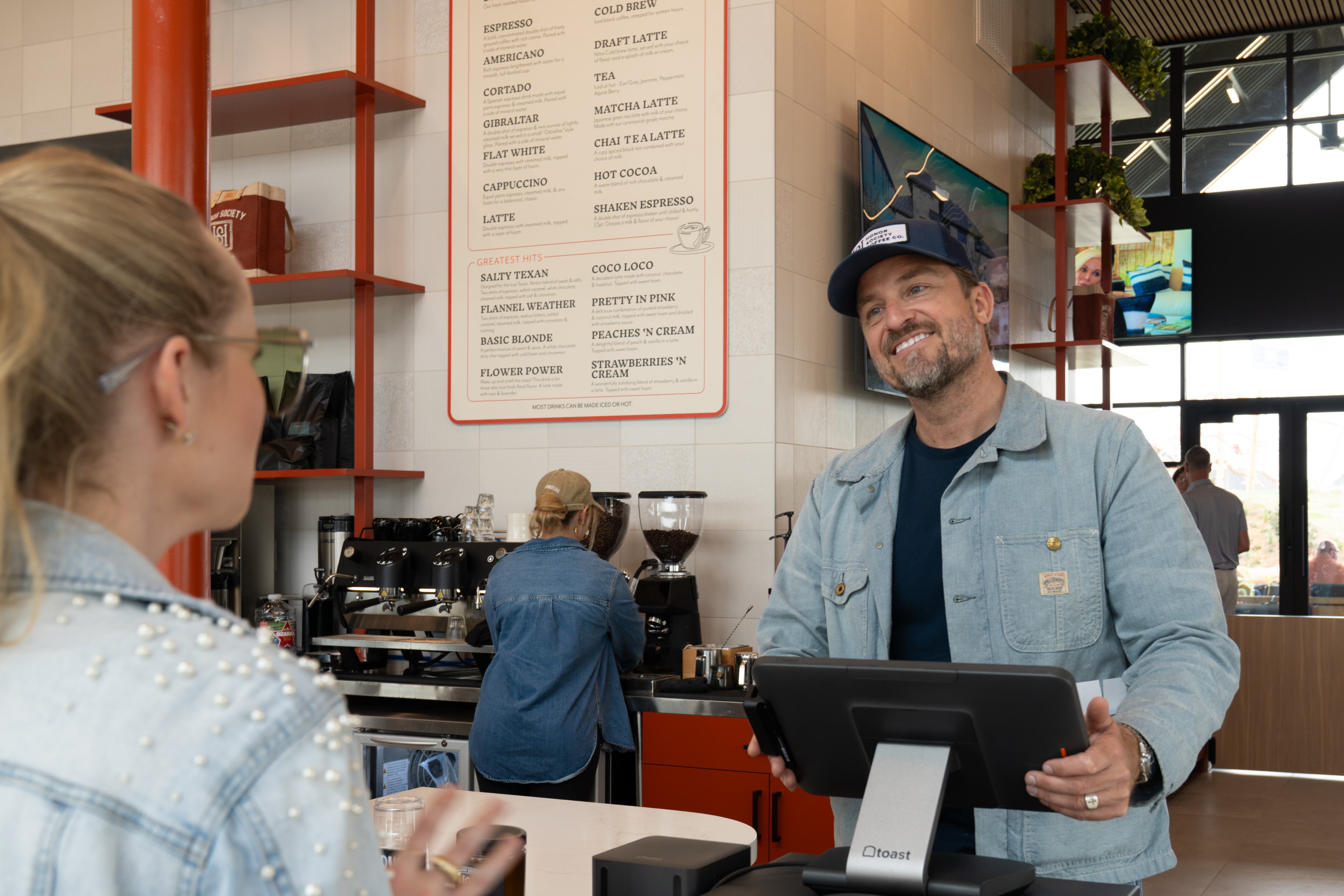 Billy Schiel, coffee company co-founder, greeting a guest at the counter in the new coffee shop.