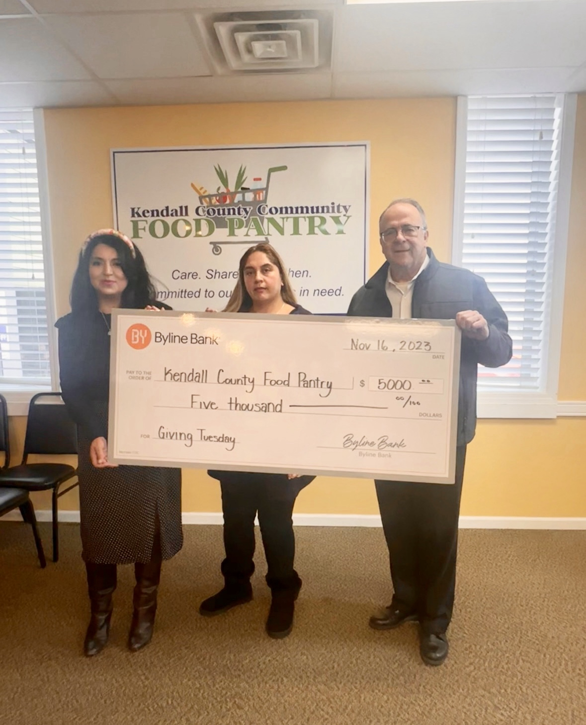 Dulce Vargas (center), Kendall County Community Food Pantry assistant director, receives a Giving Tuesday donation from Soledad Gaytan (left), manager of the Byline Bank Oswego branch, and Ken Holmstrom, Byline Bank Oswego market president.