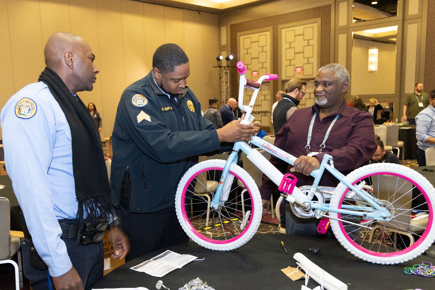 NOPD officers work with a SoundThinking employee to build a bike for New Orleans youth.