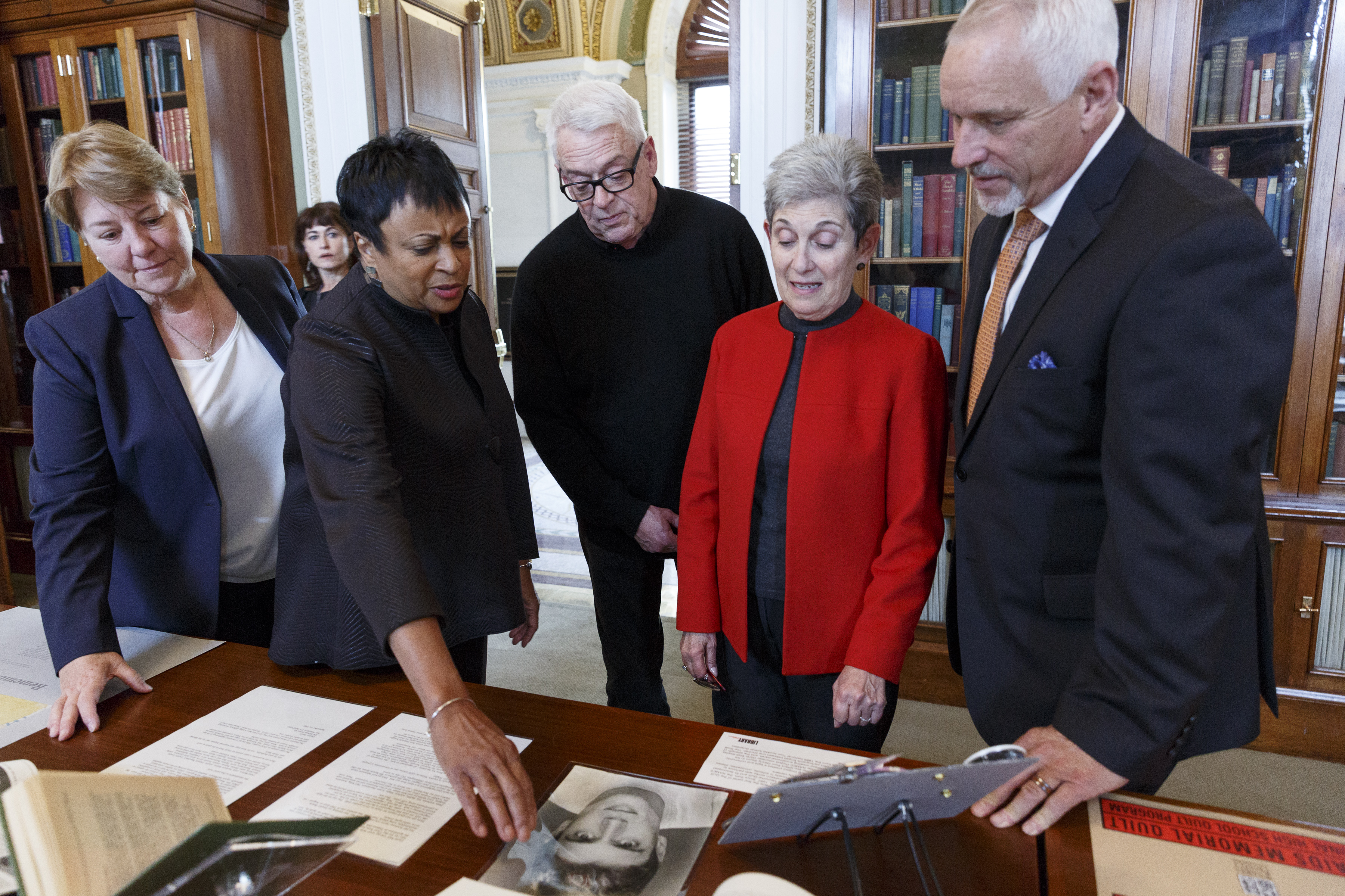 L to R: Julie Rhoad, The NAMES Project Foundation; Librarian of Congress Carla Hayden; Cleve Jones, The AIDS Quilt founder; Tina Crosby, sister of Marvin Feldman, whom the first panel was made to honor; John Cunningham, National AIDS Memorial look at a photo of Marvin Feldman as part of the archival collections that will now reside at the Library of Congress as part of an announcement today that also will move the more than 50,000 panels of The AIDS Quilt back to San Francisco where it was started 32 years ago.  Photo Credit: Shawn Miller, Library of Congress