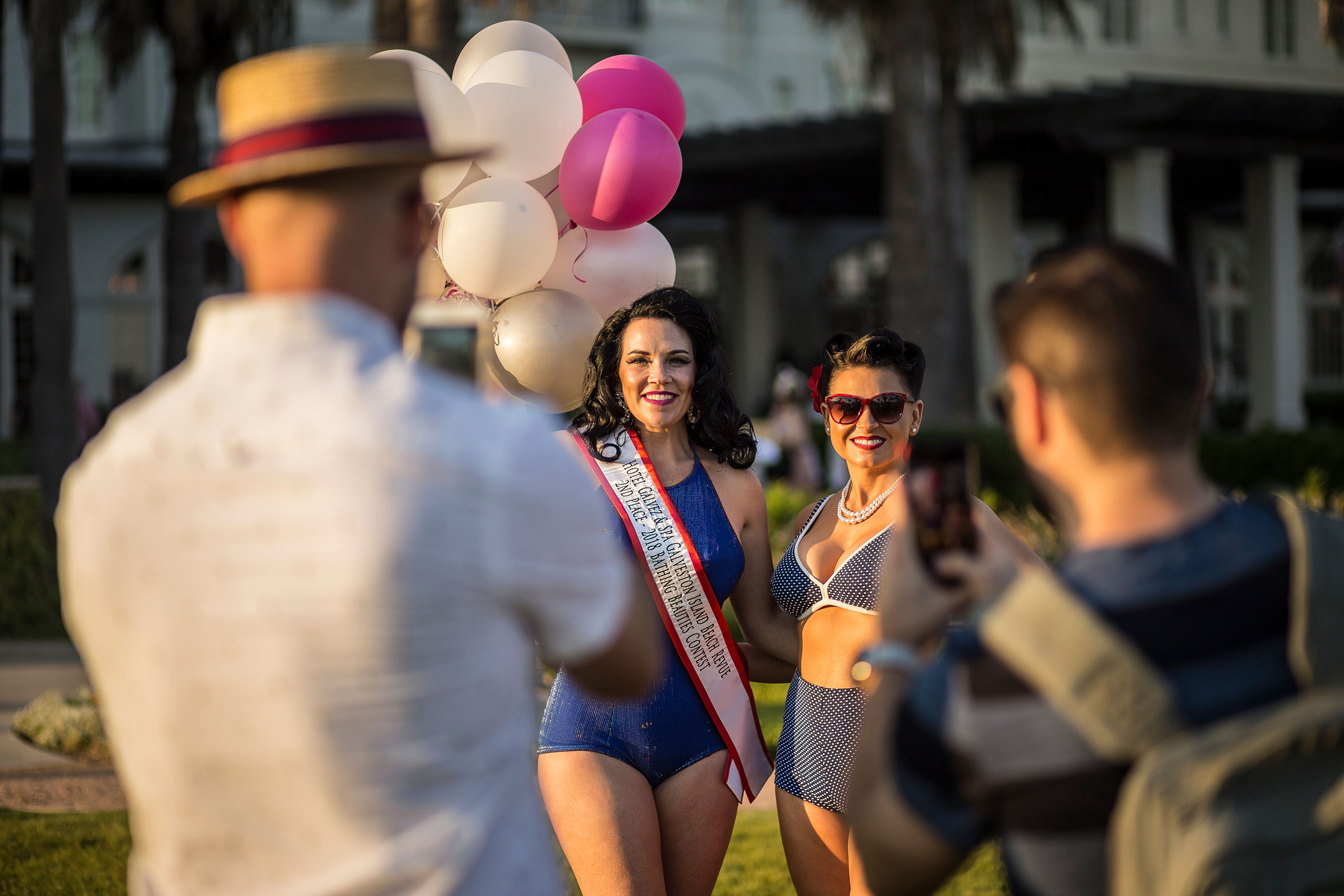 Jennifer Hillhouse of Mesa, AZ and Hayley Cochran of College Station, TX pose for photographers in front of the Hotel Galvez & Spa, adjacent to the Galveston Island Beach Revue festival grounds.