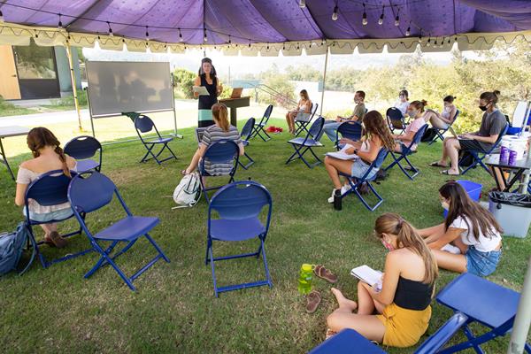 Andrea Gurney, Westmont professor of psychology, teaches masked and socially distant students under a tent on Winter Lawn. 