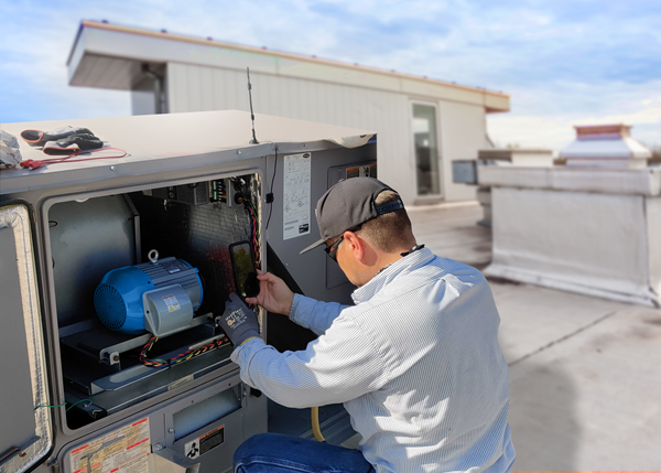 Technician on a rooftop in front of HVAC motor