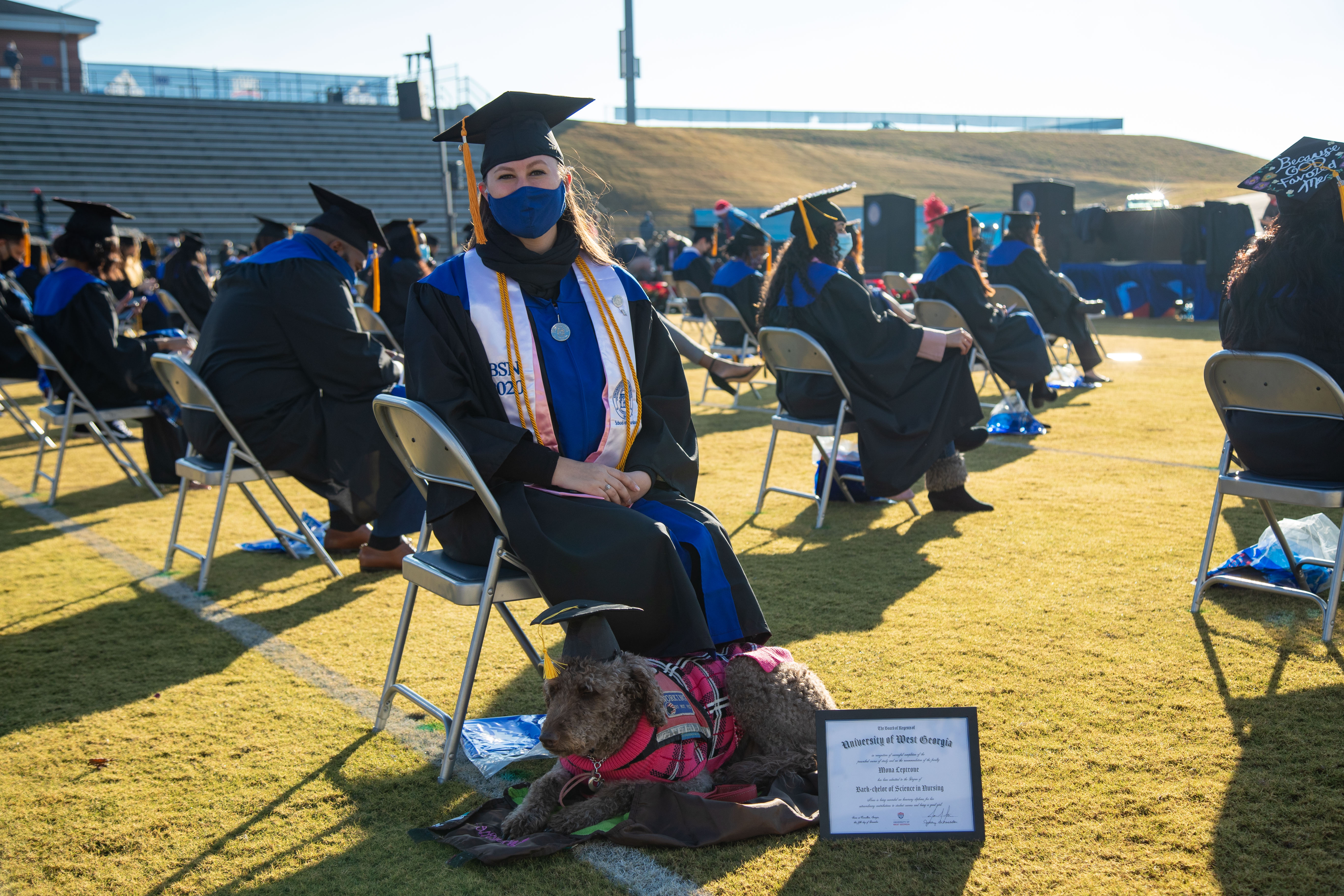 Maggie Leptrone, a nursing student at the University of West Georgia, sits with her Diabetic Alert Dog, Mona, before the university's Commencement ceremony began Saturday. Mona, a Labradoodle trained to detect changes in blood sugar, accompanied Leptrone in all of her classes, clinicals and labs and received an honorary degree from the university Saturday.