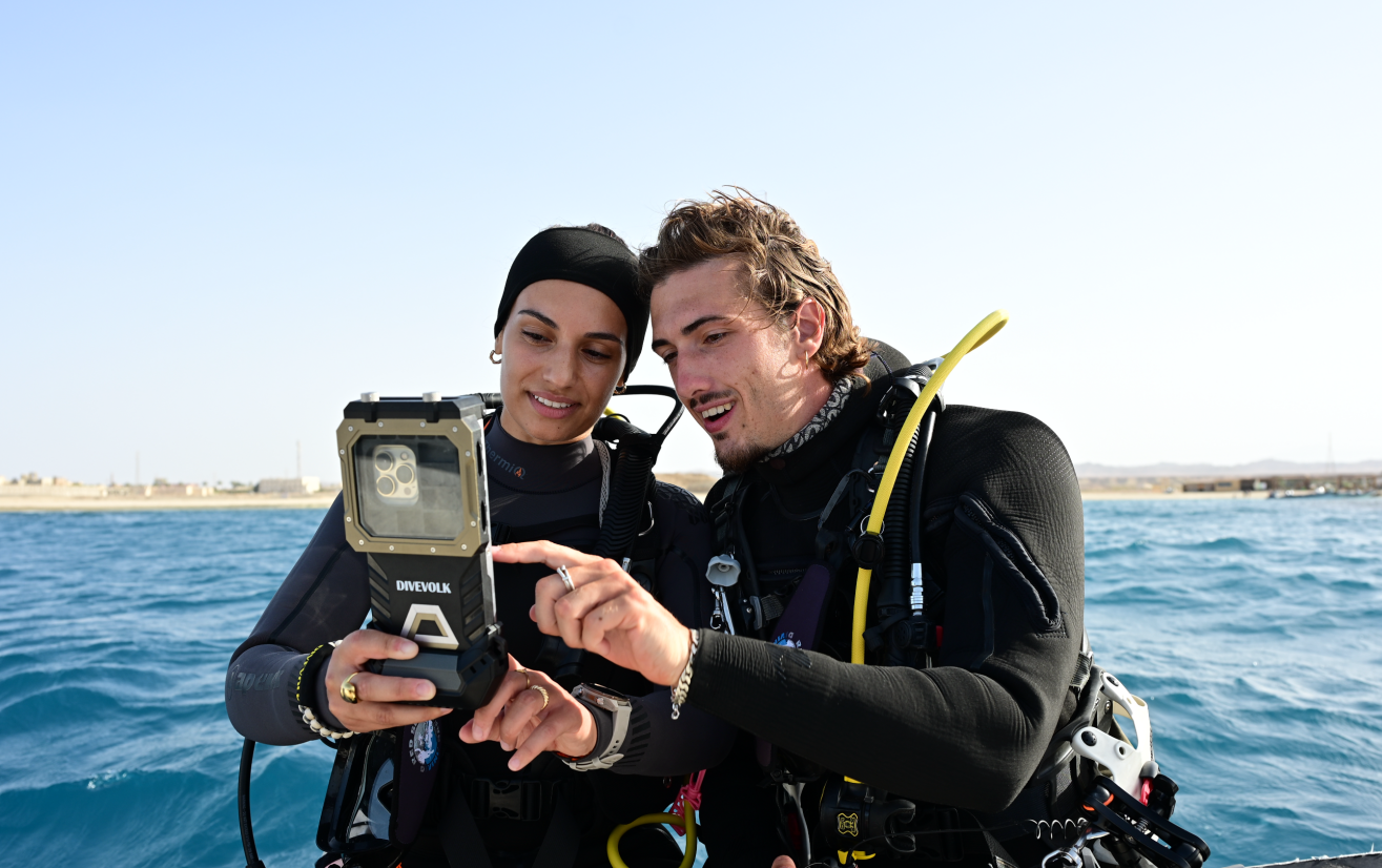 Two divers with a DIVEVOLK housing at the surface, where GPS and cellular signals remain usable through the case
