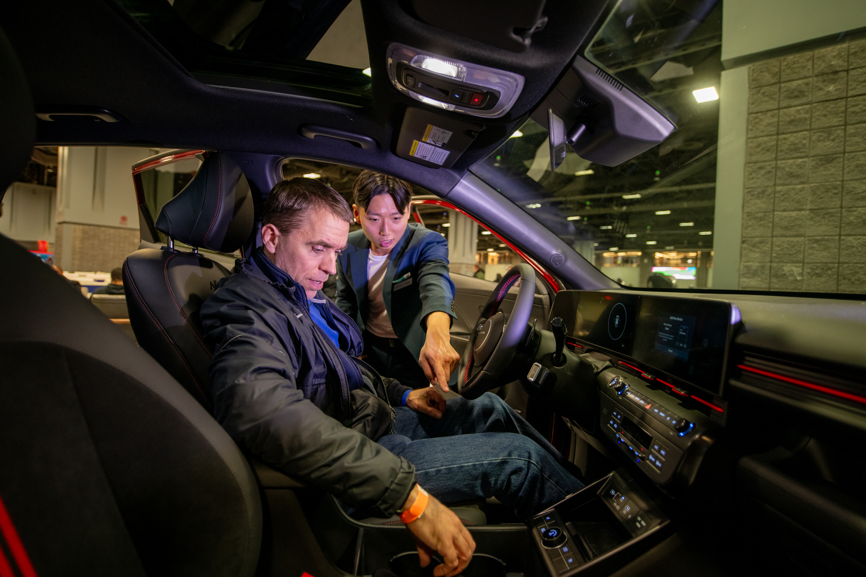 Automaker representatives showcasing the latest technology in their new models on the show floor.