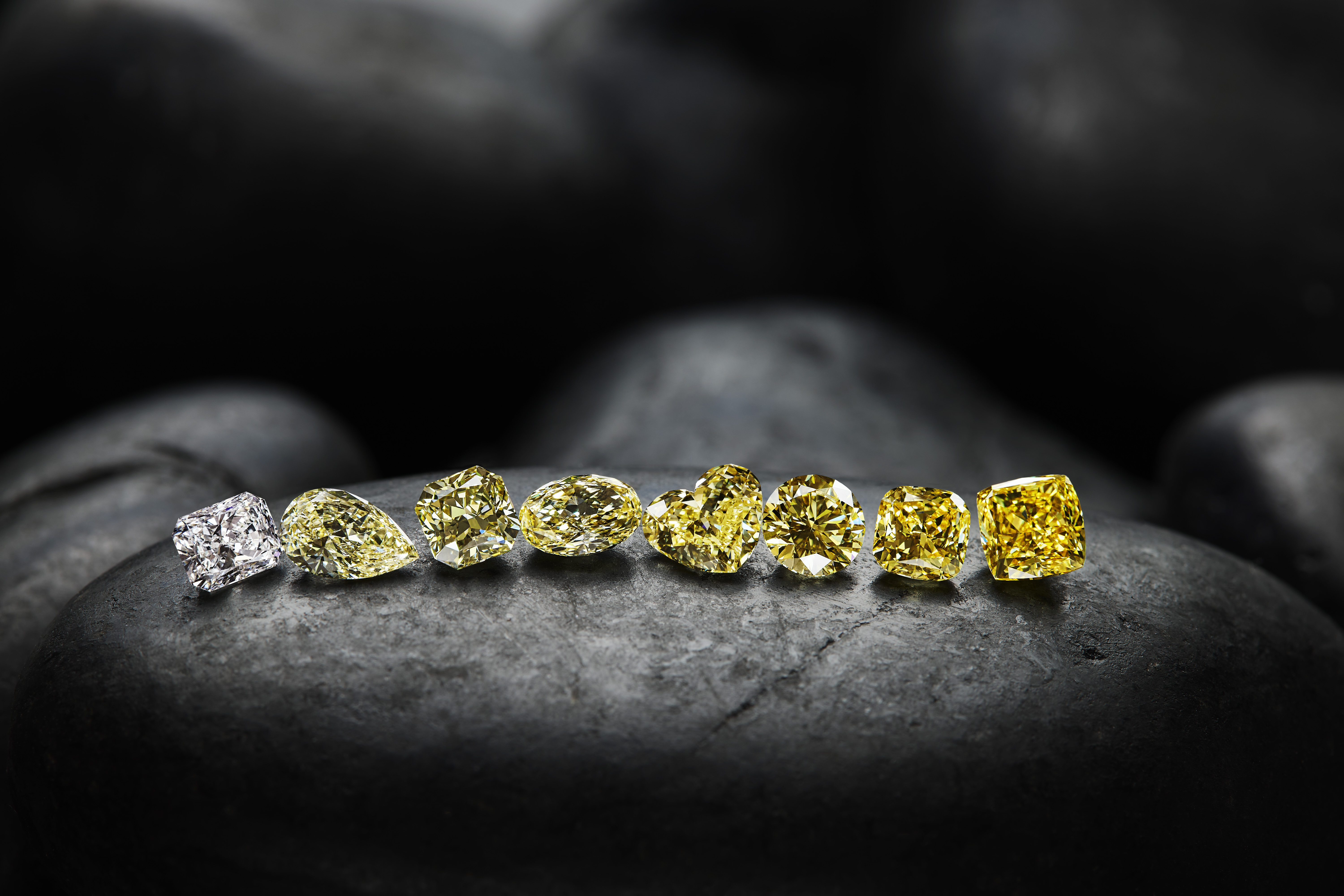 A mix of Burgundy Diamond Mines polished diamonds lined up on a dark background.
