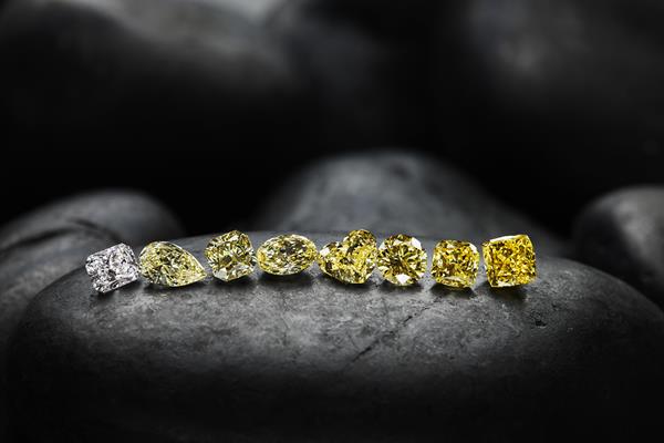 A mix of Burgundy Diamond Mines polished diamonds lined up on a dark background.