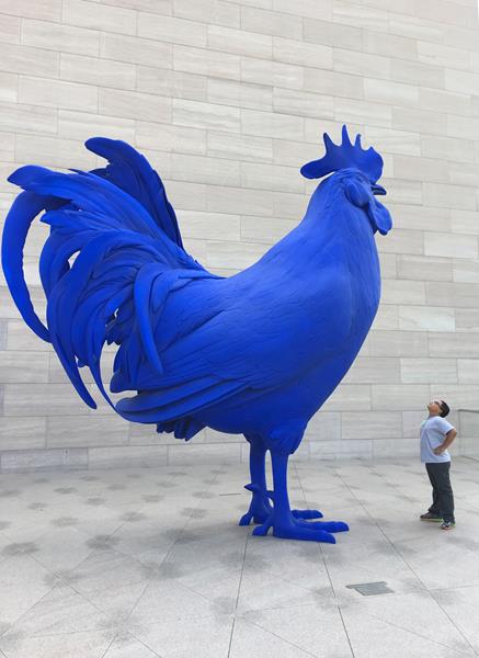 A visitor stands looking at "Hahn/Cock" (2013) by Katharina Fritsch on the National Gallery of Art’s East Building Roof Terrace
glass fiber reinforced polyester resin fixed on stainless steel supporting structure
overall: 440.06 × 440.06 × 149.86 cm (173 1/4 × 173 1/4 × 59 in.)
gross weight: 740.044 kg (1631.5 lb.)
National Gallery of Art, Washington
Gift of Glenstone Foundation 

