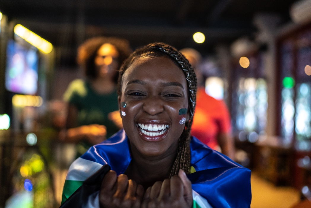 Portrait of a young woman watching a game and celebrating in a bar