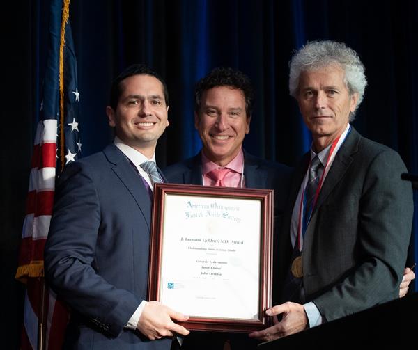 Steven L. Haddad, MD, (center) and J. Chris Coetzee, MD, (right) present the 2019 J. Leonard Goldner Award recognizing the outstanding research paper.