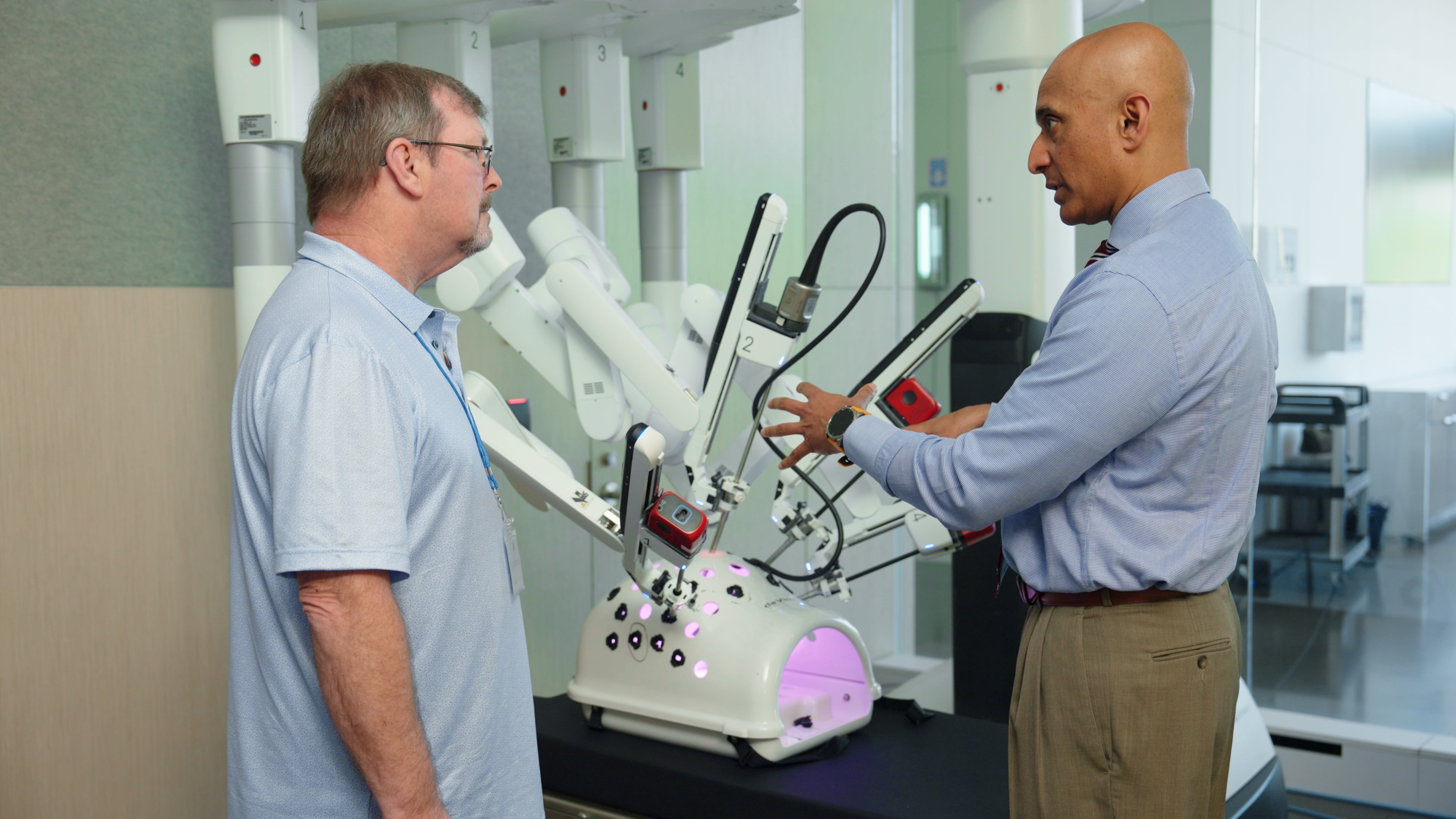 Patient Dan Larson looks on as Dr. Baiya Krishnadasan from Tacoma General explains how he used the da Vinci 5 robotic system to perform Dan's surgery.