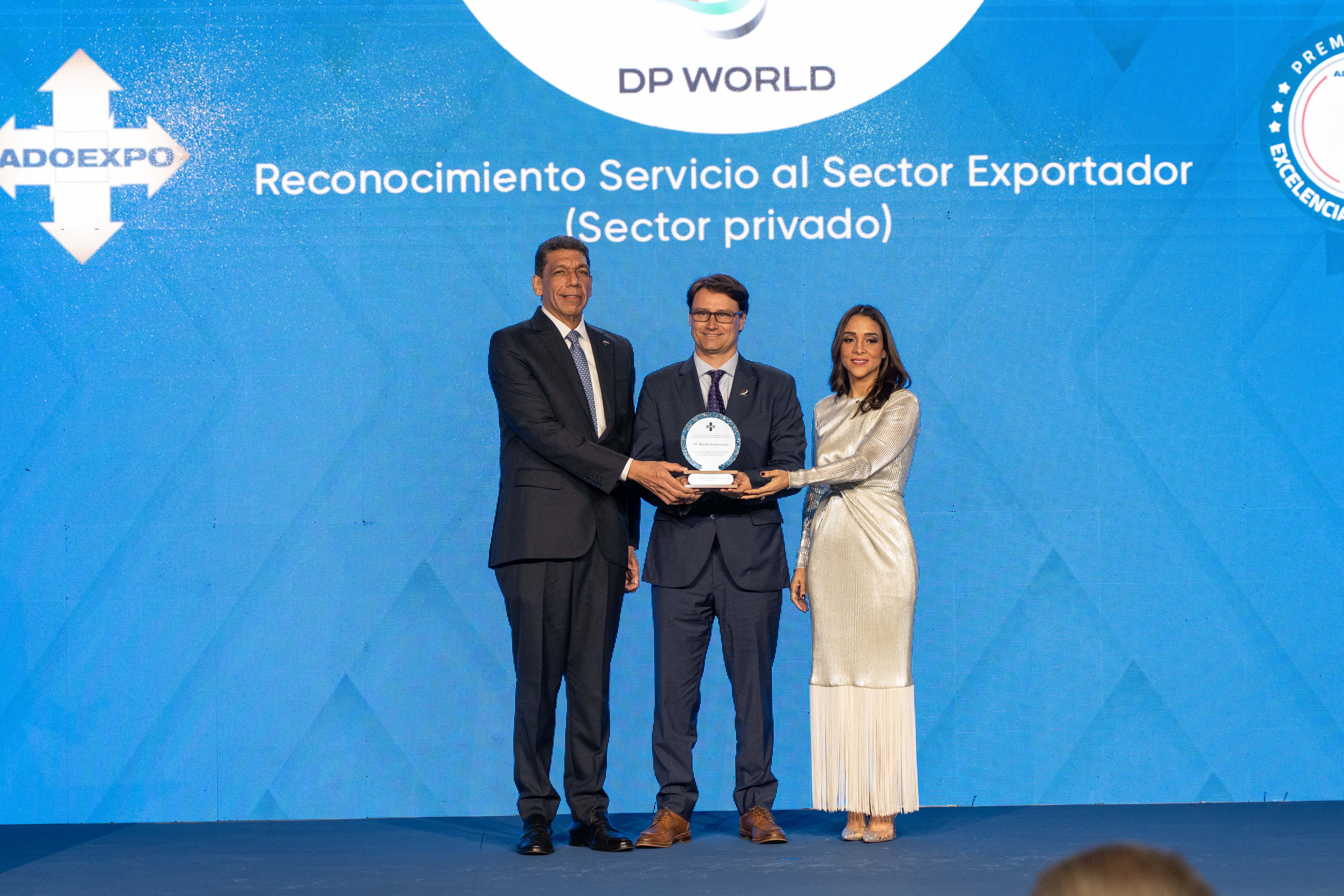 Three individuals—Karel Castillo, Manuel Martinez, and Roselyn Amaro Bergés—standing onstage as DP World receives the ADOEXPO award.
